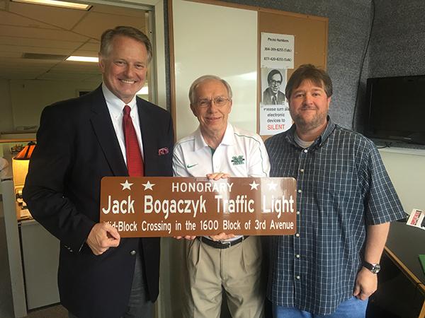 Huntington Mayor Steve Williams, left, Jack Bogaczyk and co-host Paul Swann are photographed with an honorary red light sign dedicated to Bogaczyk's years of service. 