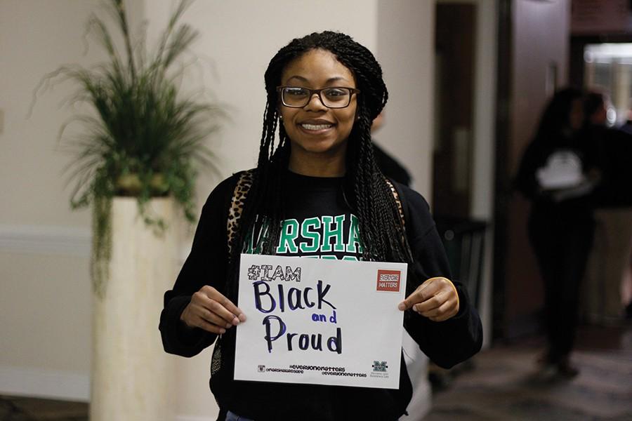 Shakaria Bowman, sophomore psychology major, holds a sign with self-describing adjectives for a selfie at the Giraffe Kisses event Monday.