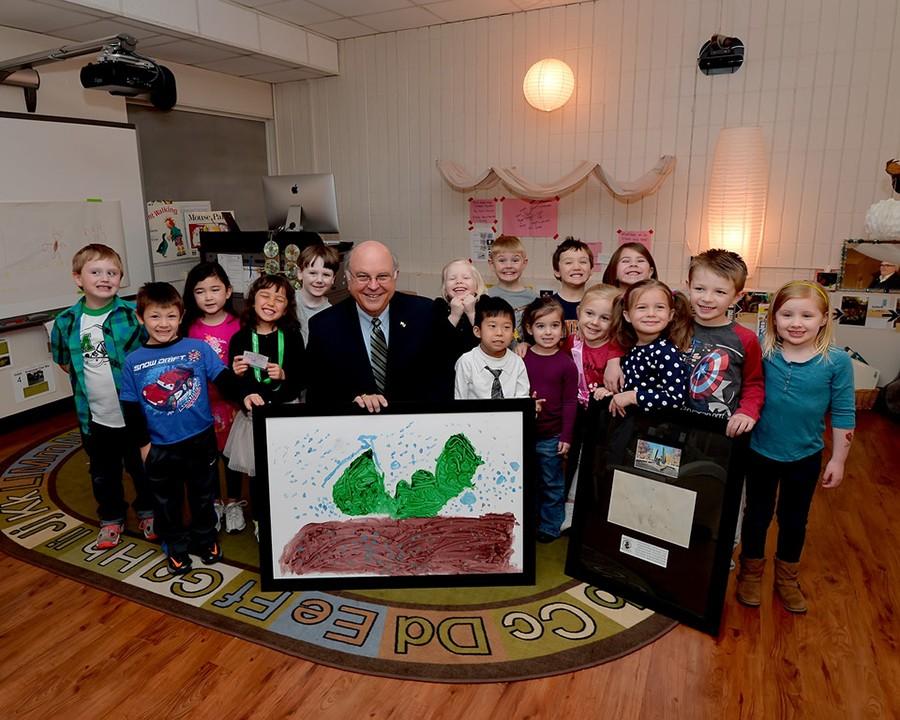 Interim President Gary White and the children pose with a picture the children drew of the Memorial Student Center fountain.