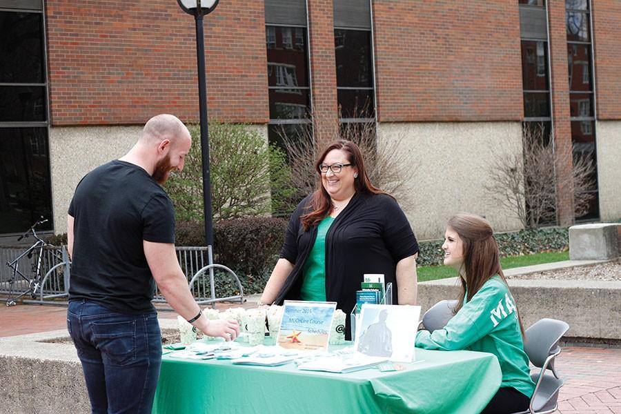 Alex Burgazzoli, graduate student in sociology, Crystal Stewart, program manager, information technology, and Alyssa Simon, student assistant, offer popcorn for students interested in finding out more about summer online classes offered through Marshall University.