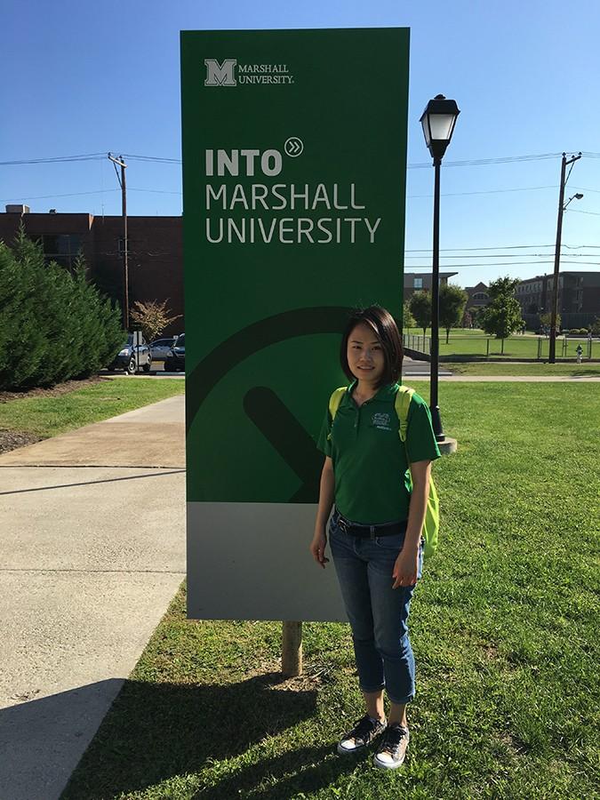 Shuo Xu standing in front of INTO sign at Marshall.