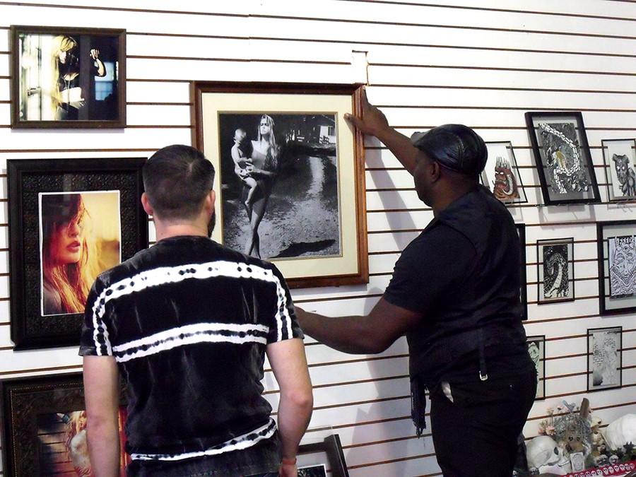 Keyamo Onage (right) , a photographer in the exhibit, hangs up his work with Joe Troubetaris (left) assisting. The art exhibit was curated by Two-Headed Dog Collective, a non-profit organization that creates temporary public safe spaces for the arts in Huntington. 