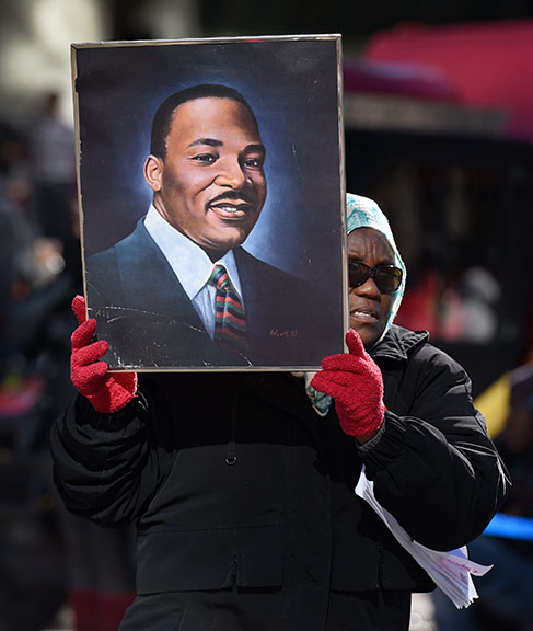 Kathy Williams walks the Martin Luther King, Jr. Day parade route with a portrait of the Civil Rights leader during the parade in Jacksonville, Fla., Monday, Jan. 18, 2016.