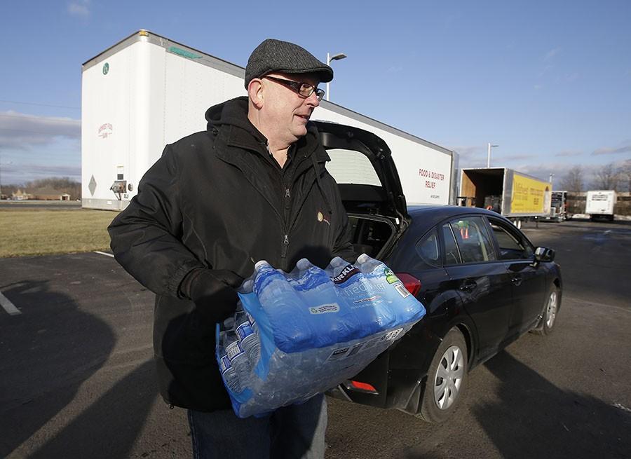 John Whitaker, executive director of Midwest Food Bank, carries a case of water that was donated, Wednesday, Jan. 27, 2016, in Indianapolis. All of the water that was collected will be sent to Flint, Mich., where drinking water has been contaminated by lead.