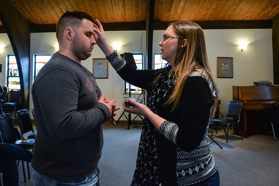 Traci Ferguson, Marshall University campus minister, traces ashes onto the foreheads of students for Ash Wednesday at the Catholic Newman Center.