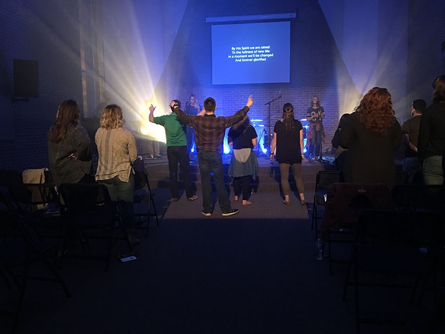 Students raise their hands in prayer and worship Monday night at a special Easter InsideOut service.