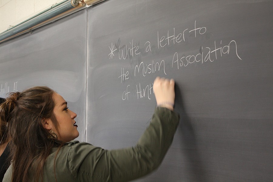 Treasurer of Marshalls Amnesty International chapter Kristin Wallace writes information for the letter-writing campaign on the blackboard in room 529 of Smith Hall.