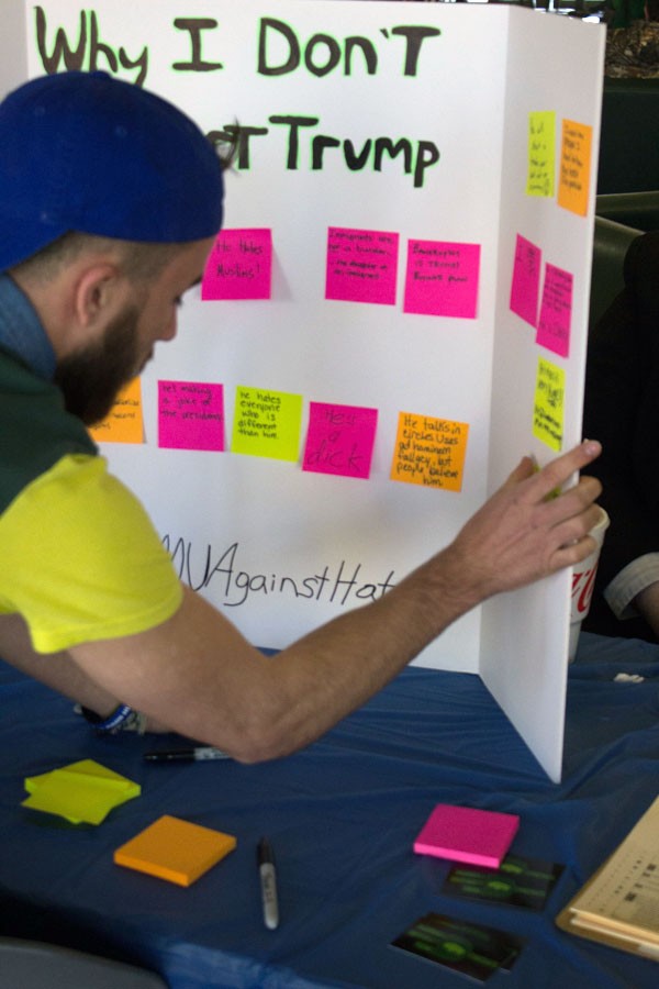 Students place sticky notes with why they don’t support Donald Trump at the Young Democrat’s #MUAgainstHate table Tuesday in the Memorial Student Center lobby.