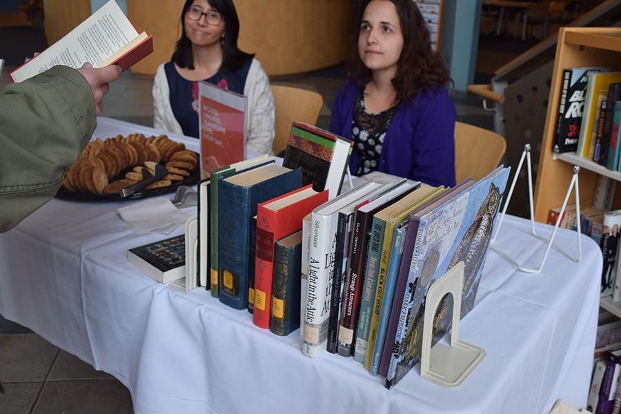 A student chooses a poem out of a book to read in exchange for a cookie Monday in Drinko Library for its Poem in Your Pocket table to celebrate National Library Week and National Poetry Month.