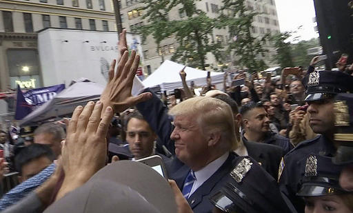 In this image made from video, Republican presidential candidate Donald Trump greets supporters outside his Trump Tower building in New York on Saturday, Oct. 8, 2016. Trump insisted Saturday he would "never" abandon his White House bid, rejecting a growing backlash from Republican leaders nationwide who disavowed the GOP's presidential nominee after he was caught on tape bragging about predatory advances on women. (AP Photo/Ezra Kaplan)
