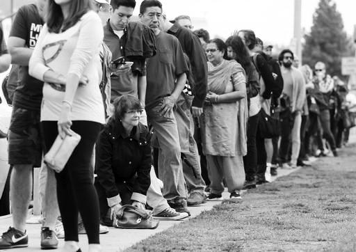 FILE - In this Oct. 30, 2016 file photo, a woman kneels to take a "back break" while waiting in line at a weekend early voting polling place at the North Hollywood branch library in Los Angeles. The FBI's disclosure that it was reviewing emails related to Hillary Clinton's email investigation will make no difference to tens of millions of voters who have already cast ballots.  (AP Photo/Reed Saxon, File)