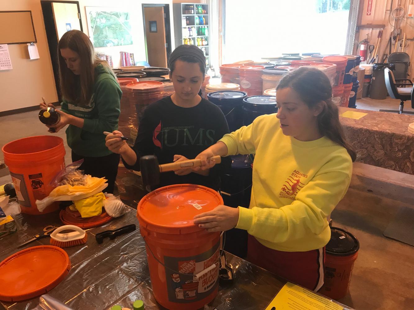 United Methodist Students members and Marshall University sophomores (from left to right) Kayleigh Terrel, Jennifer Gerst and Betsy Horton mark up items and hammer down lids on flood buckets to be sent to survivors of Harvey and Irma hurricanes.