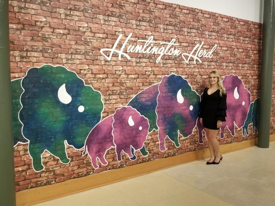 Senior Karianne Fischer stands by her Huntington Herd mural, unveiled Monday during the second tier of senior capstone exhibitions at the Visual Arts Center. 