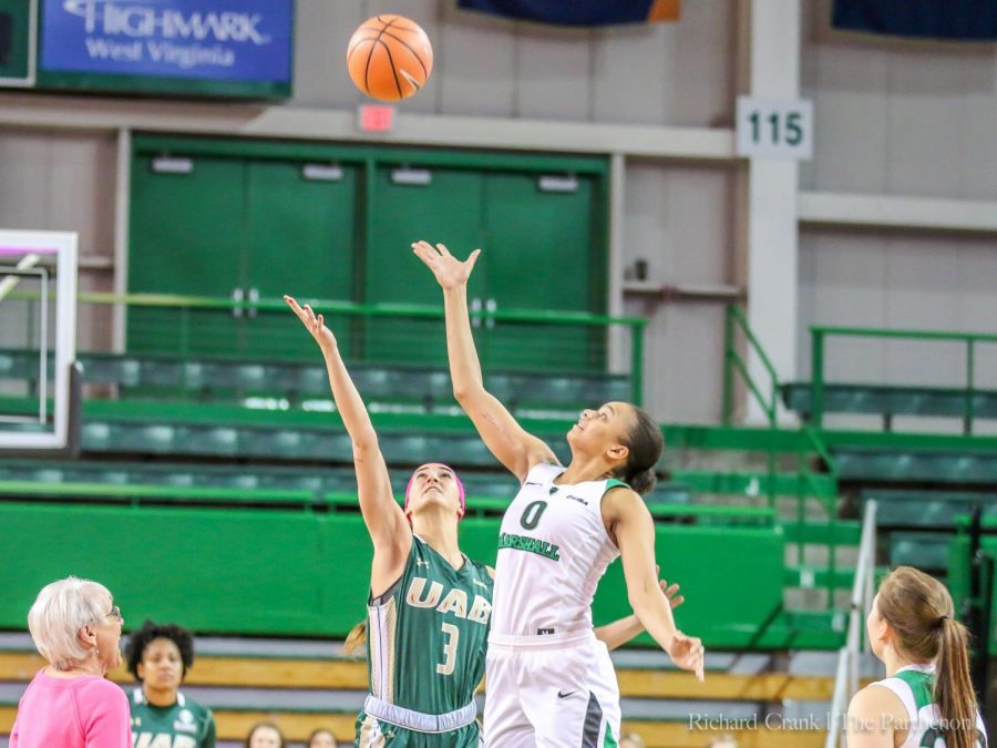 Marshall's Talequia Hamilton (0) and UAB's Angela Vendrell (3) rise for the honorary jump ball, thrown by head Coach Tony Kemper's mother (left).