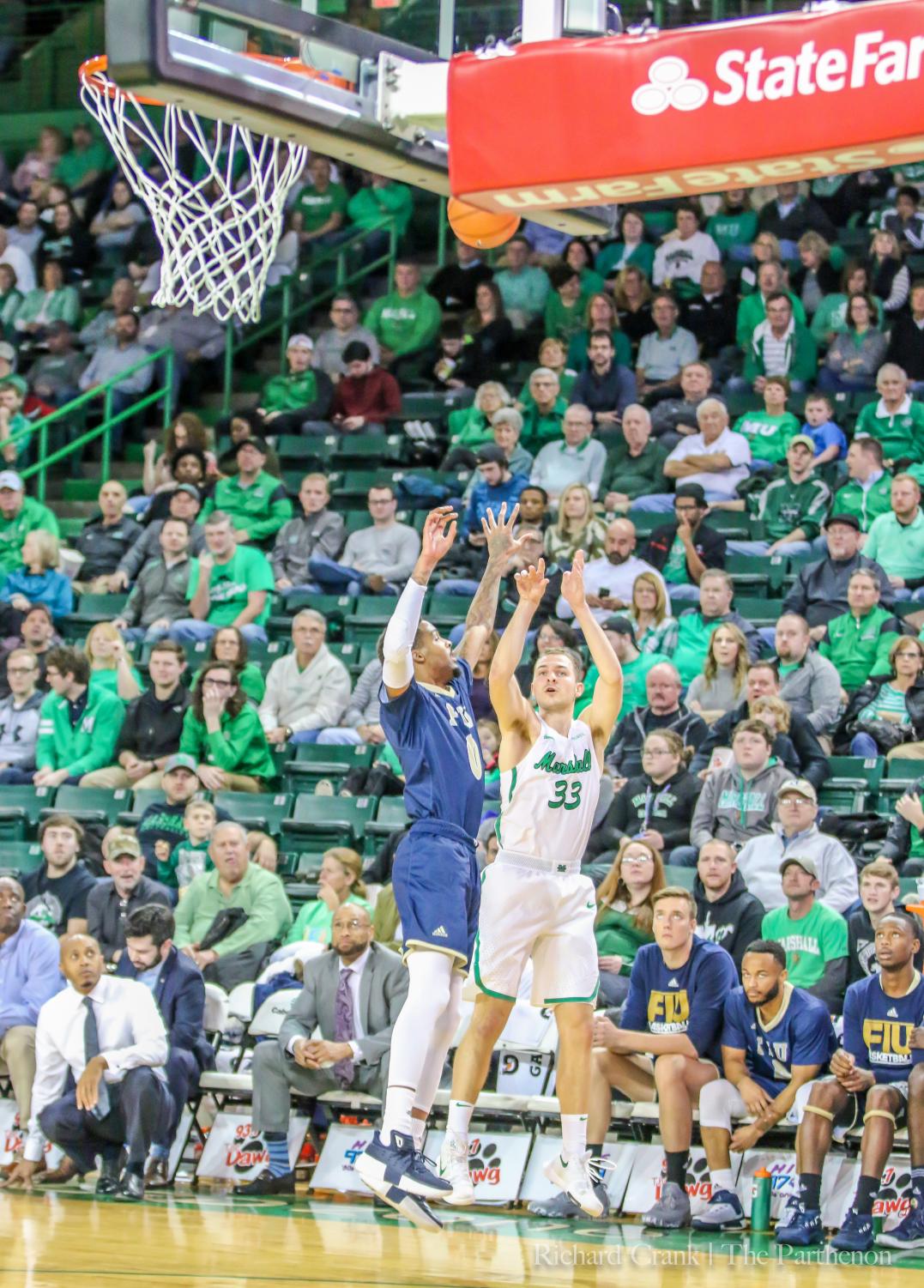 Junior Guard Jon Elmore shoots a 3-pointer around an FIU defender. Elmore's shooting from beyond the arc is a staple in Marshall's offense.