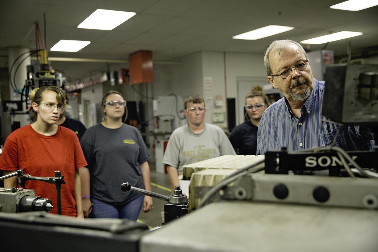 Machinist instructor Rick Smoot, right, demonstrates the proper use of a digital readout screen on the Clausing engine lathe for students in the Step Up for Women Pre-Apprenticeship Program at RCBI.