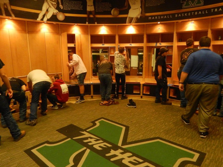 Local high school students work alongside their instructors in the Cam Henderson Center locker room. The instructors guide the students while they work hands-on.
