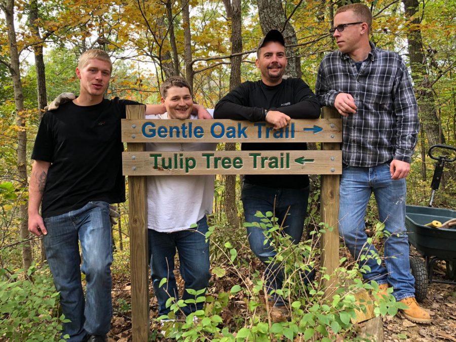 Tyler Webb (left) and fellow recovery point volunteers pose with trail signs, on a brief break from replacing hazardous steps on the paths.