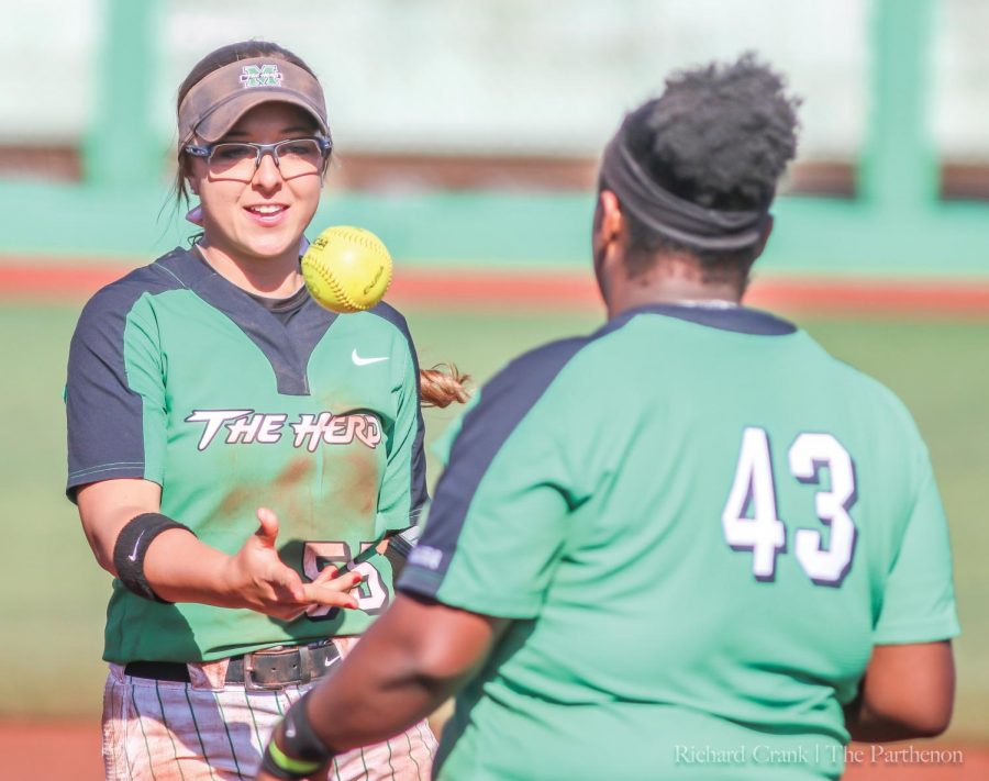 Marshall infielder Blakely Burch (55) flips the ball to Aly Harrell (43) following an out during Marshalls game at Dot Hicks Field against Morehead State on April 11, 2018.