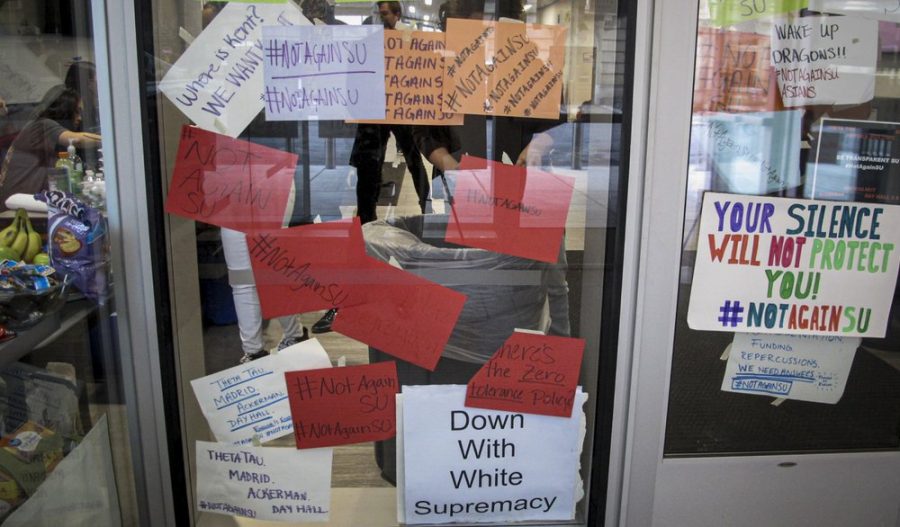 Signs posted on windows and doors at Syracuse University display anti-racism expressions, Thursday, Nov. 21, 2019, in Syracuse, N.Y. Students describe fear and anxiety as reports of racist graffiti and vandalism add up. For many, next week’s Thanksgiving break can’t come soon enough after day-after-day reports.
