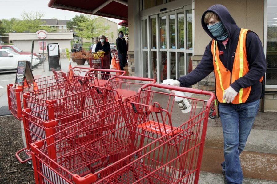 Dilon Moore disinfects shopping carts and controls the number of customers allowed to shop at one time at a Trader Joe’s supermarket in Omaha, Neb., Thursday, May 7, 2020. Store workers across the country are suddenly being asked to enforce the rules that govern shopping during the coronavirus pandemic.