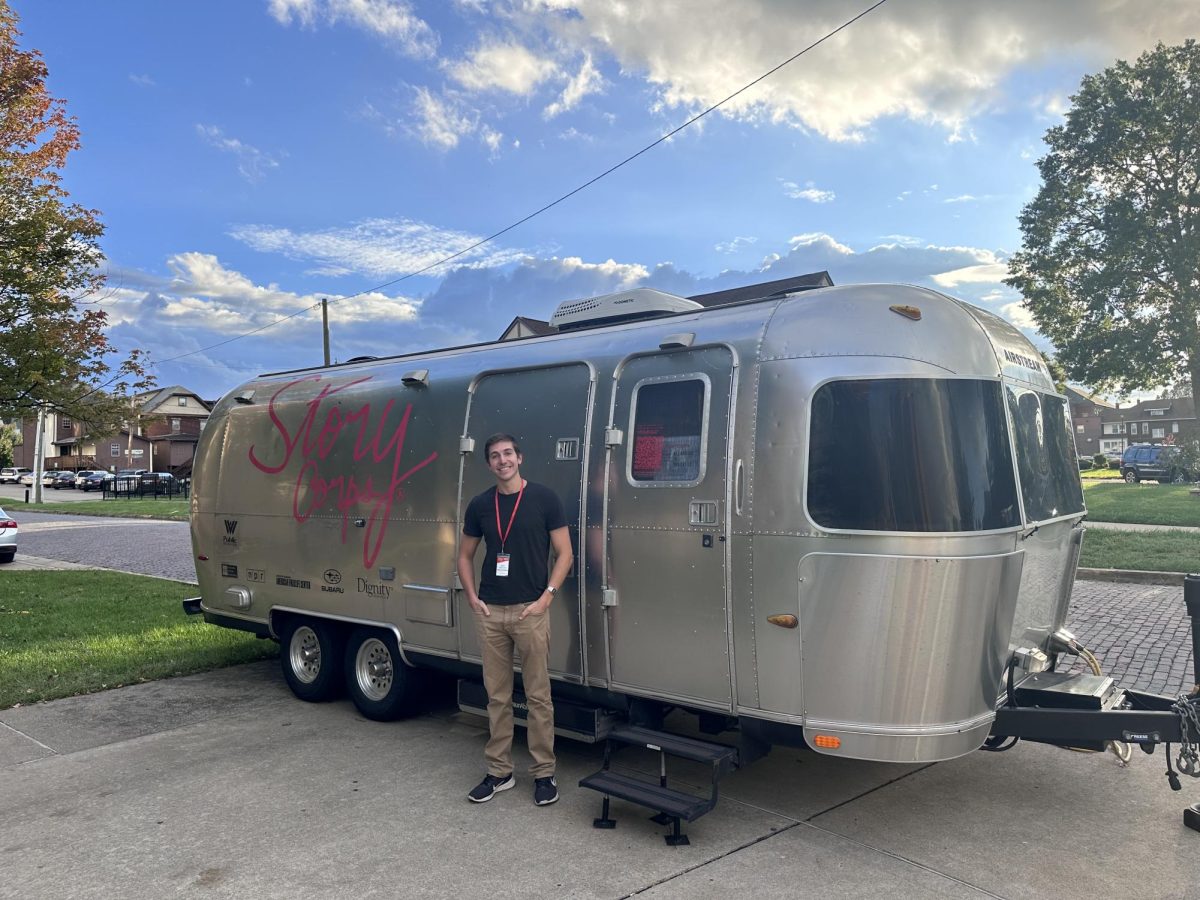 Sam Berkrot stands in front of the StoryCorps Airstream Bus.