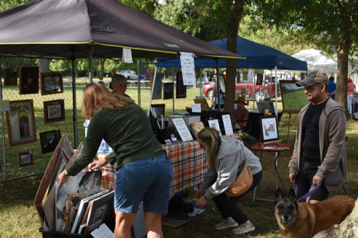 Visitors look through artwork at Steve and Debbie Sisson's booth. 